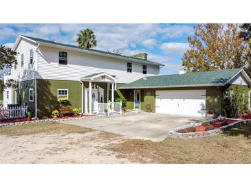 Charming two-story home with a green roof, white trim, and an attached two-car garage at 13131 Mountain Vw, Clermont, FL 34715