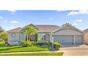 Charming single-story home featuring a manicured lawn, mature landscaping, and a three-car garage at 3530 Mulberry Grove Loop, Leesburg, FL 34748