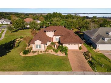 Luxury home with circular driveway, landscaped yard, and lake view at 38728 Oak Place Ct, Lady Lake, FL 32159