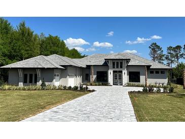 Beautiful gray one-story home featuring an extended driveway and manicured landscaping with blue skies overhead at 16914 Vinci Way, Bella Collina, FL 34756