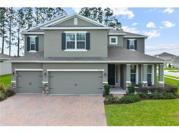 Two-story house with gray siding, three-car garage, and landscaped lawn at 2150 White Dahlia Dr, Apopka, FL 32712