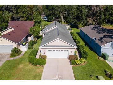 Charming home featuring a well-manicured lawn, beautiful landscaping, and an oversized two car garage at 973 Belle Oak Dr, Leesburg, FL 34748