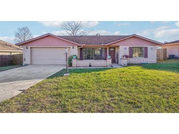 Charming single-story home with a brick facade, a well-manicured lawn, and an attached garage at 1907 E Chapel Dr, Deltona, FL 32738