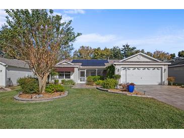 Single-story home with solar panels, landscaped yard, and two-car garage at 3550 Auburndale Ave, The Villages, FL 32162