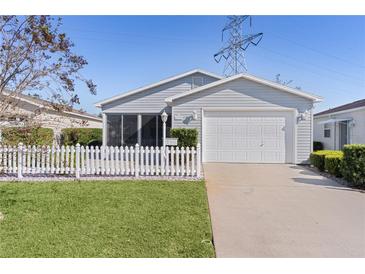 Gray house with white picket fence and attached garage at 1639 Campos Dr, The Villages, FL 32162