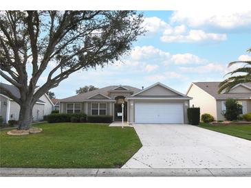 One-story house with a white garage door and landscaped lawn at 1897 Caryle Ln, The Villages, FL 32162