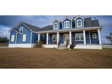 Charming blue two-story home featuring a welcoming front porch with stylish columns and a landscaped front yard at 2437 Bay Lake Loop, Groveland, FL 34736