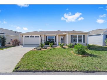 Charming single-story home with a well-manicured lawn, inviting curb appeal, and a two-car garage at 320 Zingale Ln, The Villages, FL 32163