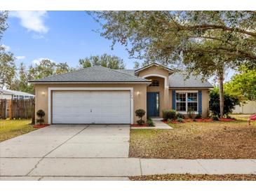 Tan house with white garage door and landscaping, offering curb appeal at 1575 Whooping Dr, Groveland, FL 34736