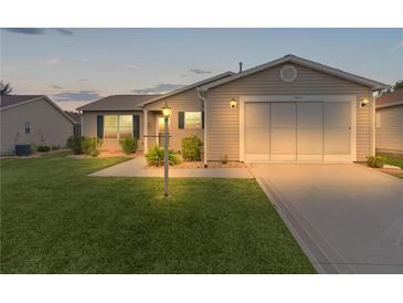Tan house with a garage and landscaped lawn at 17466 Se 75Th Coachman Ct, The Villages, FL 32162