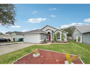 Gray house with red door, white garage door, and landscaped lawn at 2633 Winchester Cir, Eustis, FL 32726