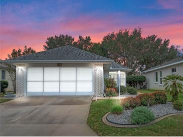 Brick ranch home with grey roof, screened garage, and landscaped yard at 5520 Sir Churchill Dr, Leesburg, FL 34748