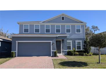 Two-story house with gray siding, a brick driveway and landscaping at 1710 Summer Rose Dr, Mount Dora, FL 32757
