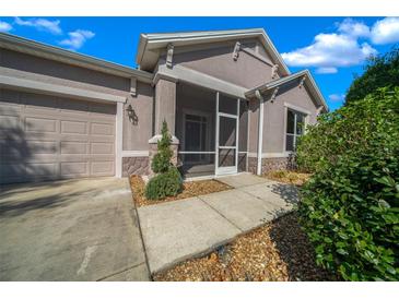 The house features a screened front entry, an attached garage, and manicured landscaping at 1828 Feliciana Ter, The Villages, FL 32162
