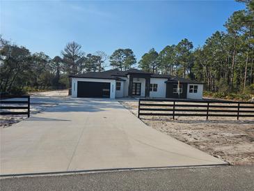 Modern two-story home with a large driveway and a fenced yard at 42157 Tamarac St, Eustis, FL 32736