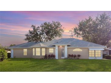 Tan house with gray roof, white trim, and landscaping; dusk photo at 5622 King James Ave, Leesburg, FL 34748