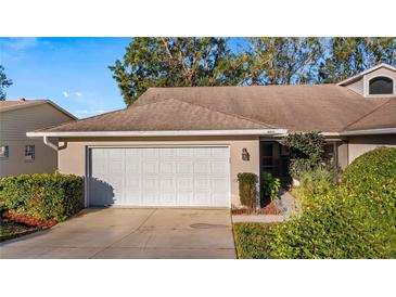 Inviting exterior of a single-story home with a two-car garage and manicured landscaping at 8801 Village Green Blvd, Clermont, FL 34711