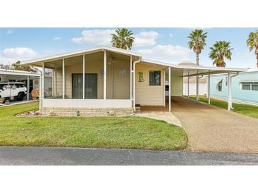 Charming single-story home featuring a covered carport, screened in porch, and tropical landscaping at 12 Hilly Way, Fruitland Park, FL 34731