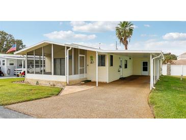 Charming single story home featuring an attached carport, a screened in porch, and a well-maintained lawn at 12 Hilly Way, Fruitland Park, FL 34731