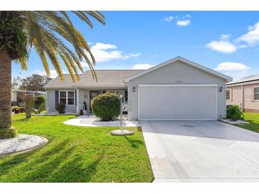 Single-story home with gray siding, attached garage, and well-manicured lawn at 1228 Zapata Pl, The Villages, FL 32159