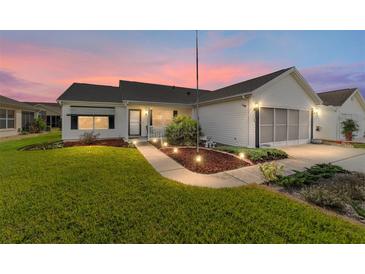 Well-maintained house with a landscaped lawn and a two-car garage at 1904 De Hoyos Pl, The Villages, FL 32159