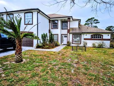 Two-story house with white exterior, brown accents, and a landscaped yard at 3180 Sixma Rd, Lake Helen, FL 32744
