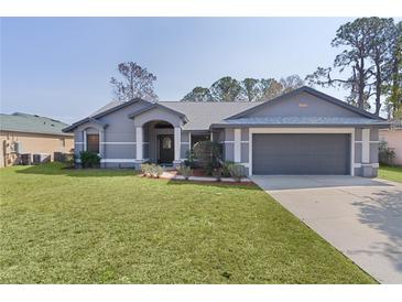 Charming single-story home with a well-maintained lawn, neutral gray paint, and attached two car garage at 35534 Quail Run, Leesburg, FL 34788