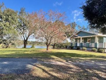 Single story home with lake view, front porch, and mature trees at 43140 Hossin Around Ln, Altoona, FL 32702