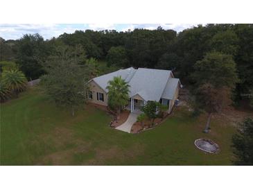 Single-story home with a large yard, located in a wooded area at 9622 Dr Baker Rd, Groveland, FL 34736