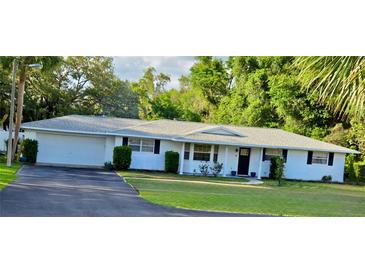 Charming single-story home with a manicured lawn, black shutters, and a two-car attached garage at 2937 Eagles Nest Rd, Fruitland Park, FL 34731