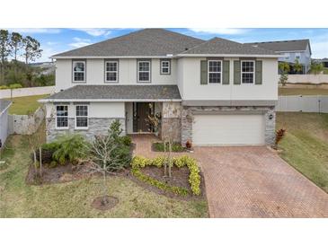 Two-story home with stone accents and a brick driveway at 410 Cheeota Ct, Minneola, FL 34715