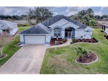 Single-story home with gray roof, white walls, and landscaped yard at 5626 Squires Dr, Leesburg, FL 34748