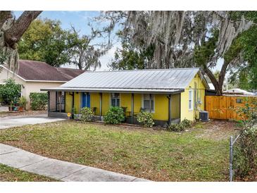 Yellow house with metal roof, screened porch, and yard at 1319 Stowe Ave, Mount Dora, FL 32757