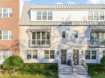 Two-story townhome with gray metal roof, white and brick exterior, and front balconies at 133 S Park Ave, Winter Garden, FL 34787