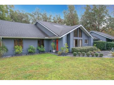 Gray house with landscaped yard, red door, and unique architectural details at 1701 Cedar Stone Ct, Lake Mary, FL 32746