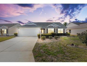 Charming one-story house with a landscaped lawn and attached garage at 2304 Jonebury Run, The Villages, FL 32162