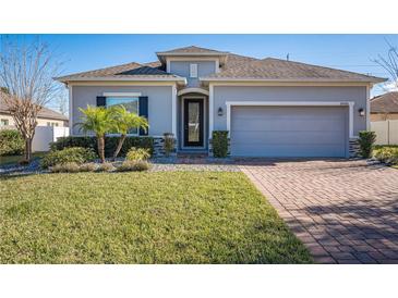 One-story home with gray siding, brick accents, and a two-car garage at 24506 Woodhill Ct, Sorrento, FL 32776