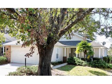 Single-story home with brick facade and attached garage, nestled amongst mature trees at 24947 Cranes Roost Cir, Leesburg, FL 34748