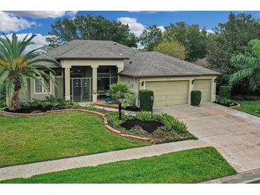 Single-story home with three-car garage, lush landscaping, and a screened porch at 27238 Stoney Brook Dr, Leesburg, FL 34748