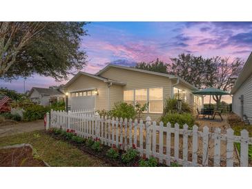 Charming home with a white picket fence, beautiful landscaping, and an inviting patio area at 2821 Barboza Dr, The Villages, FL 32162