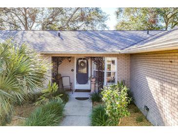 Charming brick home with a decorative metal porch, a gray door and landscaped front yard at 36703 Sandy Ln, Grand Island, FL 32735