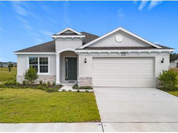 One-story house with gray siding, stone accents, and a two-car garage at 3951 Kennebunk Loop, Mount Dora, FL 32757