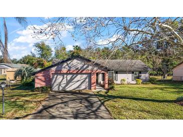 Brick ranch home with attached garage and well-manicured lawn at 401 Cherry Tree St, Eustis, FL 32726