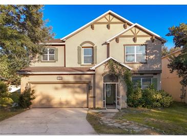 Tan two-story house with a two-car garage and landscaped yard at 5036 Gandross Ln, Mount Dora, FL 32757