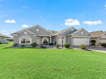 Gray two-story house with landscaped lawn and two-car garage at 12413 Se 176Th Loop, Summerfield, FL 34491