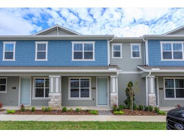 Two-story townhome with blue siding, stone accents, and landscaping at 13237 Peaceful Melody Dr, Winter Garden, FL 34787