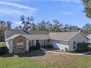 Single-story home with stone accents and a spacious lawn at 23720 Sundance Dr, Sorrento, FL 32776