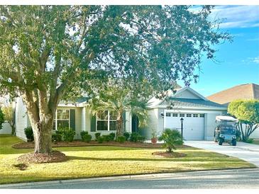 Single-story home with a two-car garage, mature landscaping, and golf cart at 2458 Dunkirk Trl, The Villages, FL 32162