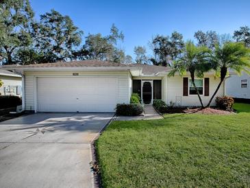 House exterior featuring a white garage door and lush green lawn at 32622 Oak Park Dr, Leesburg, FL 34748