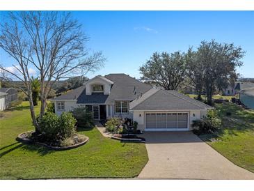 Single-story home with a gray roof, two-car garage, and nicely landscaped yard at 3546 Tropical Seas Loop, Tavares, FL 32778